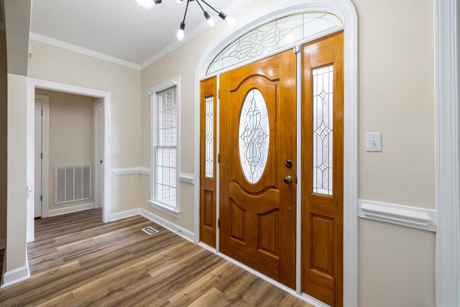 Wood-grain entry door with an oval glass insert, leaded sidelites and an arched transom