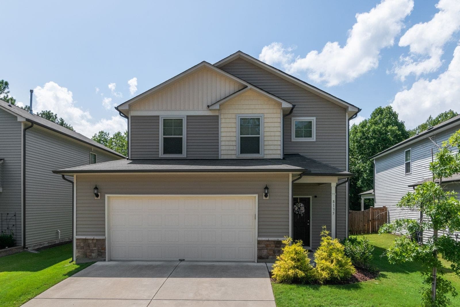 Grey sided two-storey house with a double garage and white windows