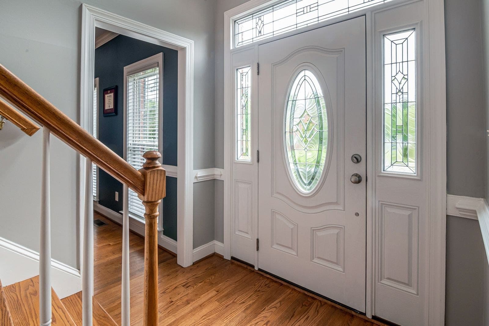 White front door with leaded oval glass, two sidelites and a transom