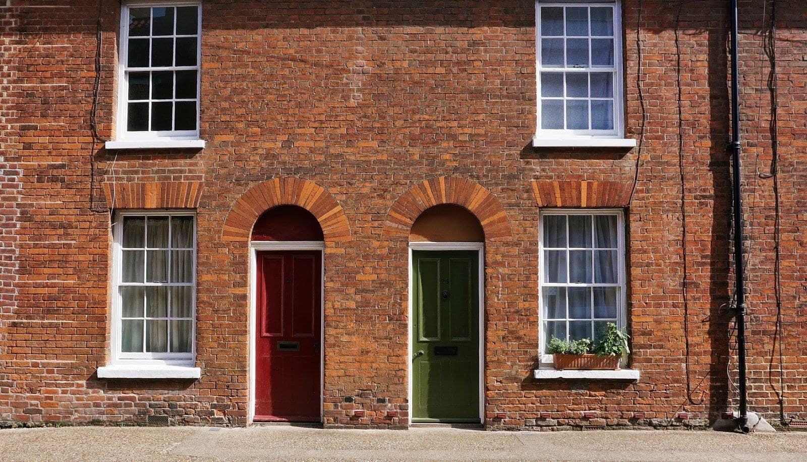 Red and green front doors under brick arches on a brick terrace