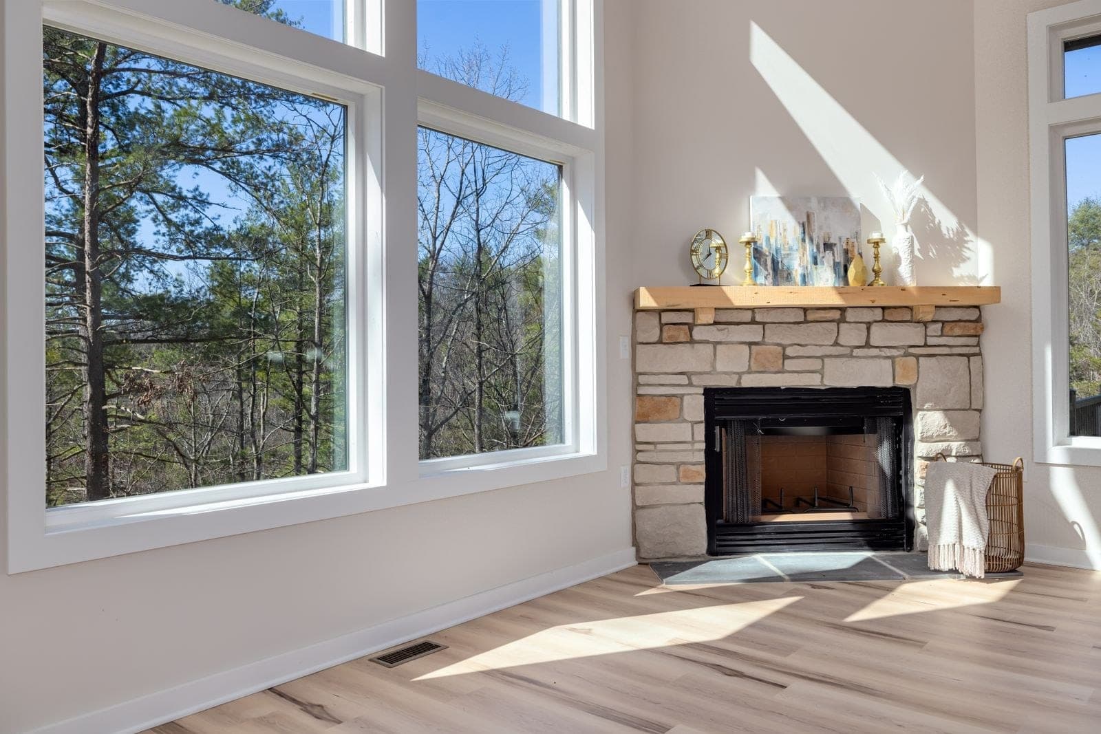 Large fixed picture windows beside a stone fireplace in a bright living room