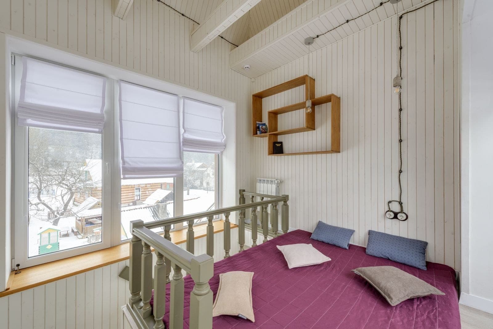 Large modern window looking out on a snowy yard from a bright loft room